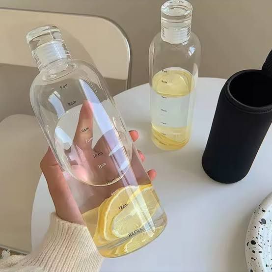Glass water bottle with time markings and lemon slice inside
