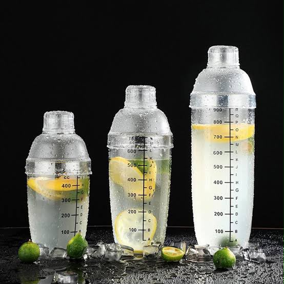 Three clear acrylic cocktail shakers with ml markings and lemon slices