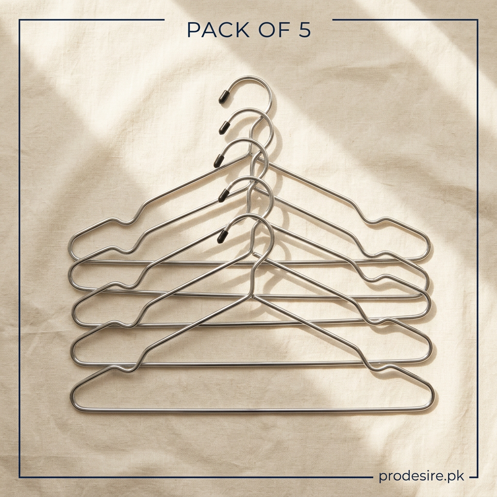 Overhead arrangement of five silver steel clothes hangers on cream linen